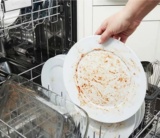 Hand putting a dirty dish in the dishwasher.