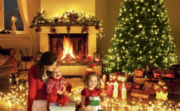 Mother and kids sitting around the Christmas tree with lighting.