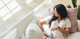 Woman on couch wearing Fitbit Luxe.