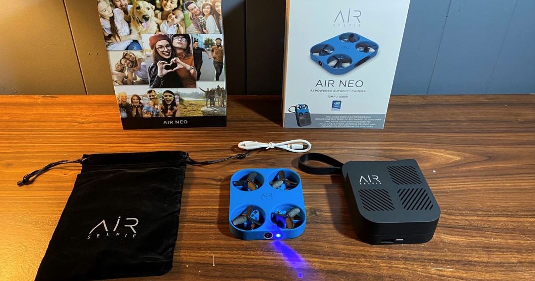 Unboxing of the AIR NEO camera Drone with all components on table, from the drone, cable, power bank and carrying bag.