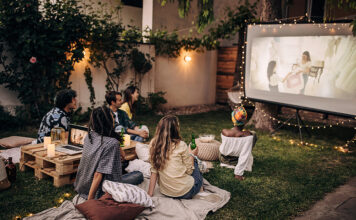 Family watching a movie on an outdoor projector.