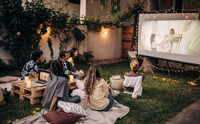Family watching a movie on an outdoor projector.