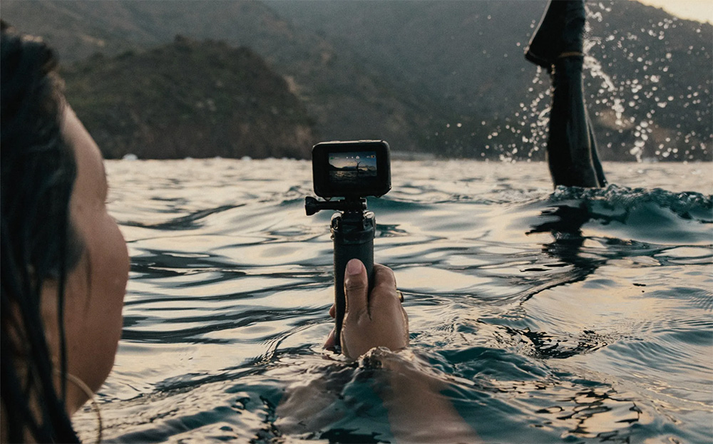 Woman taking a photo in the water with the HERO11 Black action camera. 