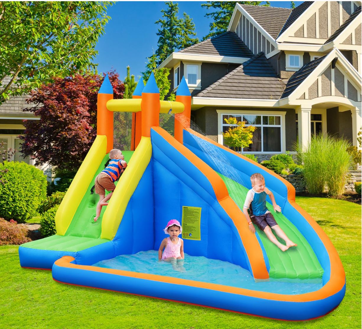 Kids playing on an inflatable water slide in a backyard.