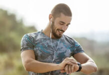 Dad with earbuds looking at a smartwatch.
