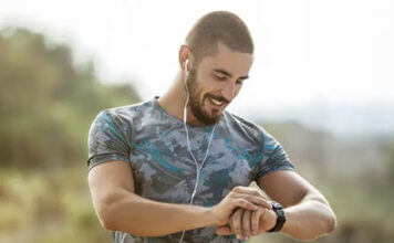 Dad with earbuds looking at a smartwatch.