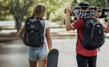 Students walking with backpacks and skateboards.