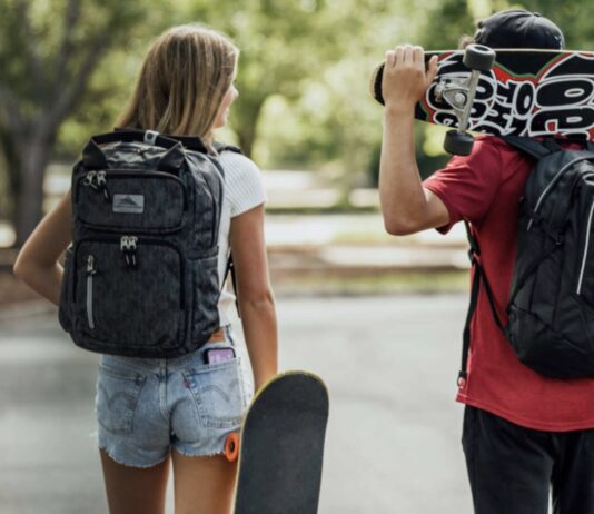 Students walking with backpacks and skateboards.