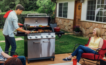 Man barbecuing and laughing with family around.