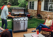 Man barbecuing and laughing with family around.