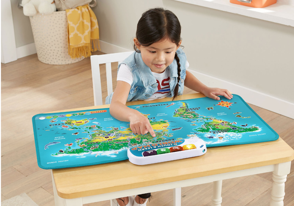 Young girl sitting at a desk and playing with the Leap Frog Touch and Learn World Map. 