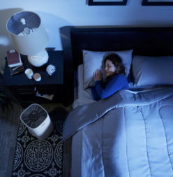 Woman asleep in bed with the Clorox air purifier.