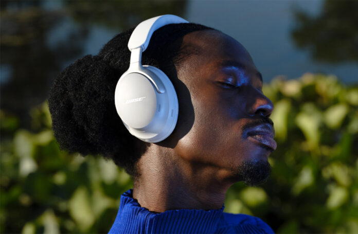 Man wearing Bose QuietComfort Ultra headphones in white.