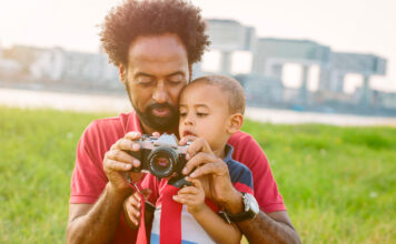 Dad with baby outside holding a camera