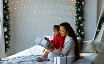 Image of a mom hugging a child with a gift in hand.