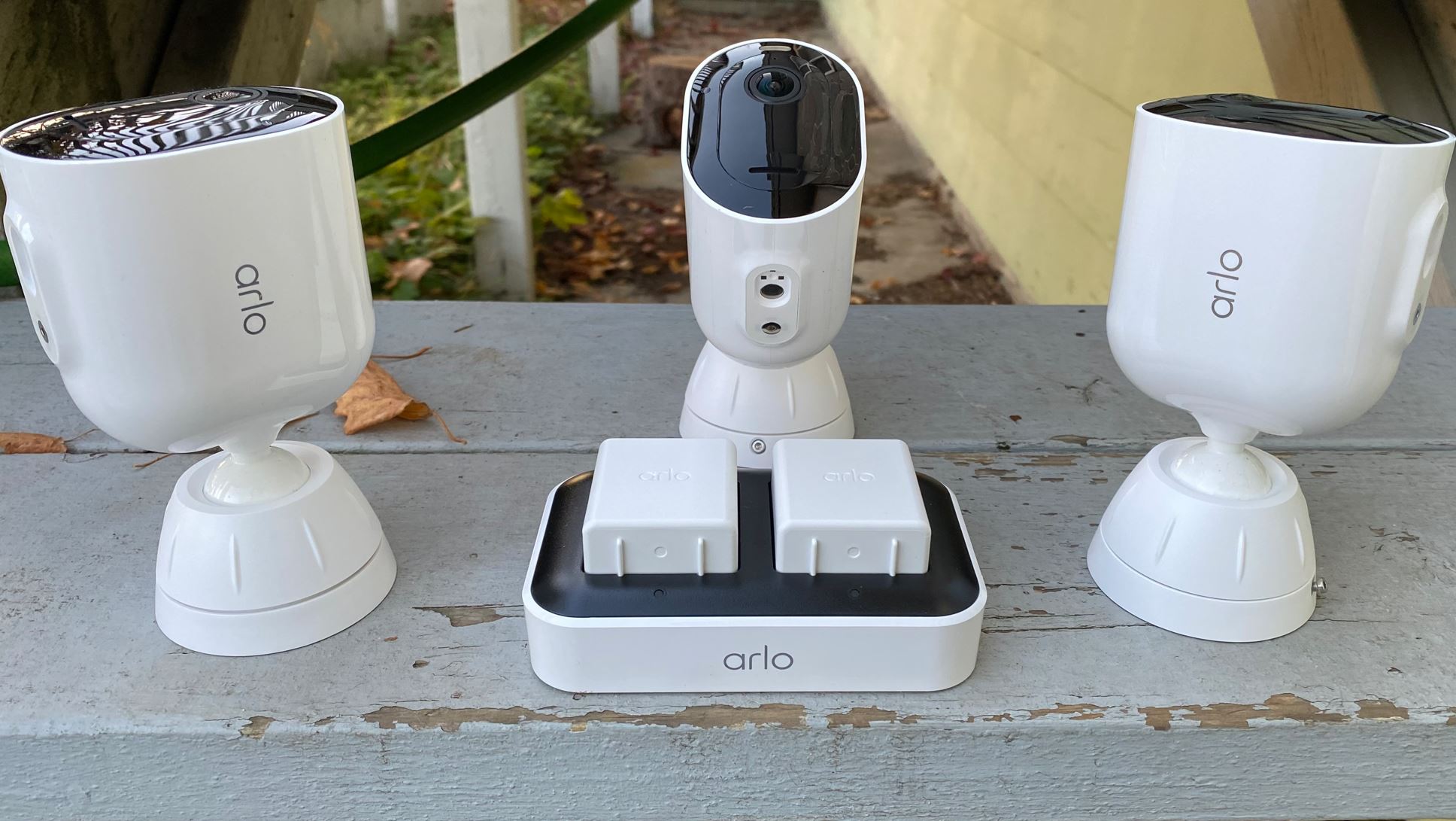 Arlo Security camera trio alongside the battery charging pack outdoors