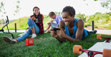 JBL Waterproof portable speaker being enjoyed by friends at a park.