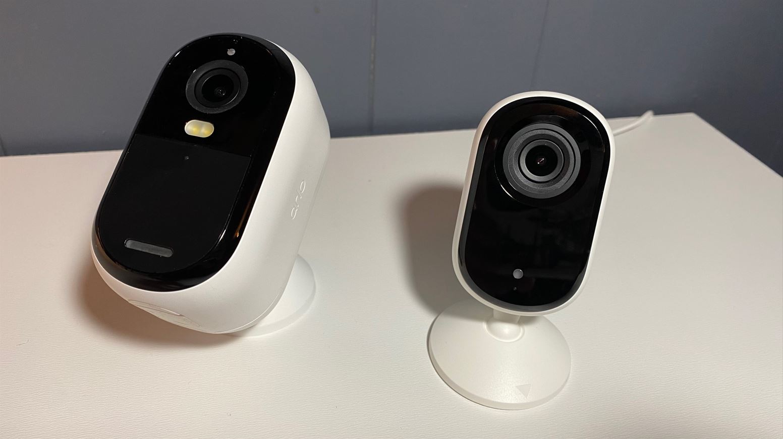 Both Arlo Essential indoor/outdoor and indoor cameras side by side on a white table