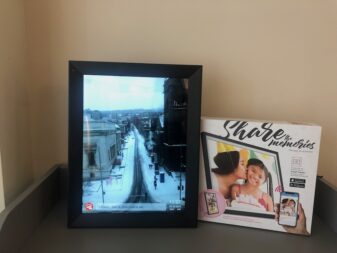 Aluratek digital photo frame displayed vertically with box. 