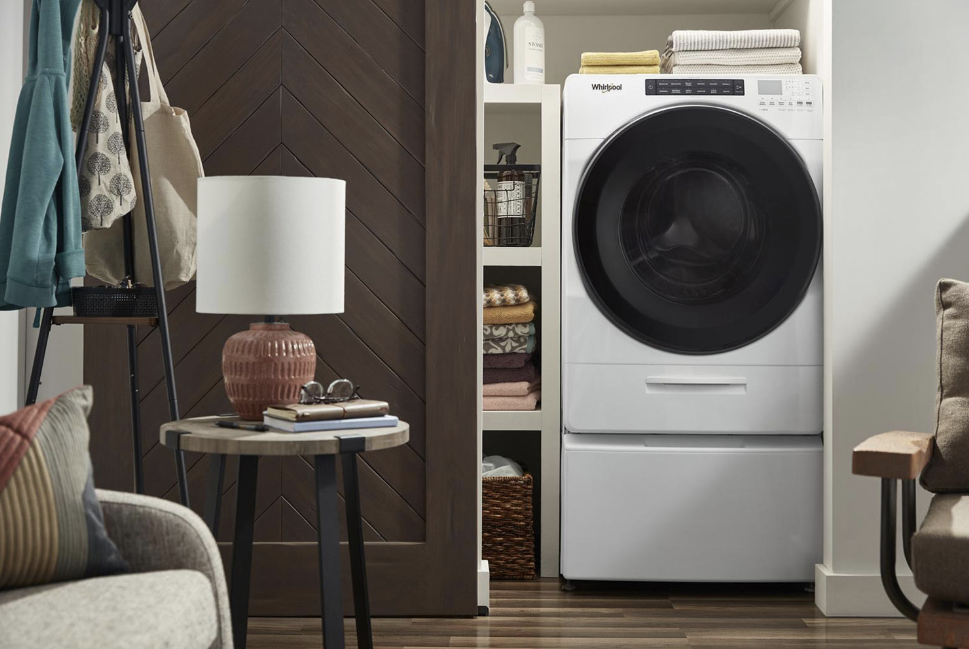Whirlpool washer/dryer combo machine installed in a small laundry space.