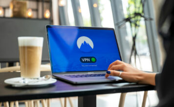Woman using VPN network on laptop in cafe.