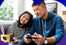 Dad and daughter playing video games side by side