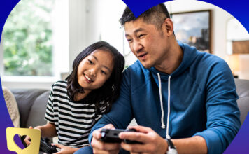 Dad and daughter playing video games side by side