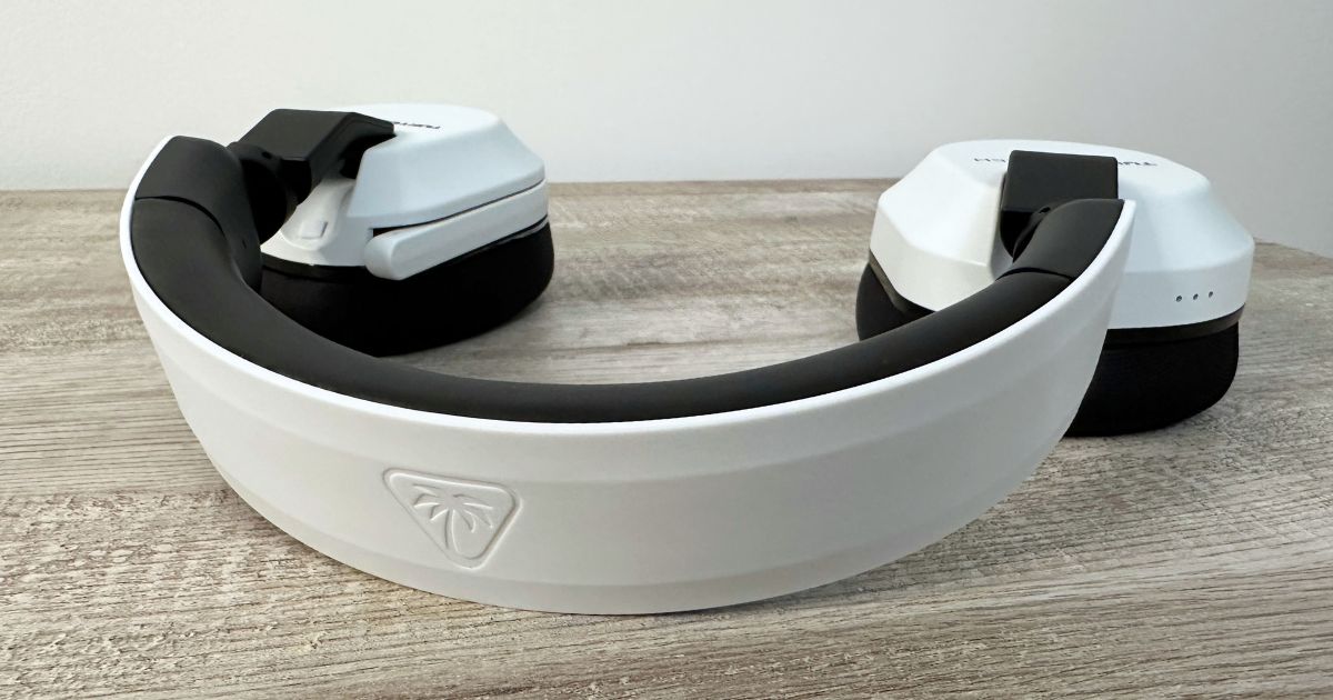 The Turtle Beach Stealth 600 headsets sit on a desk the white plastic headband facing toward the viewer.