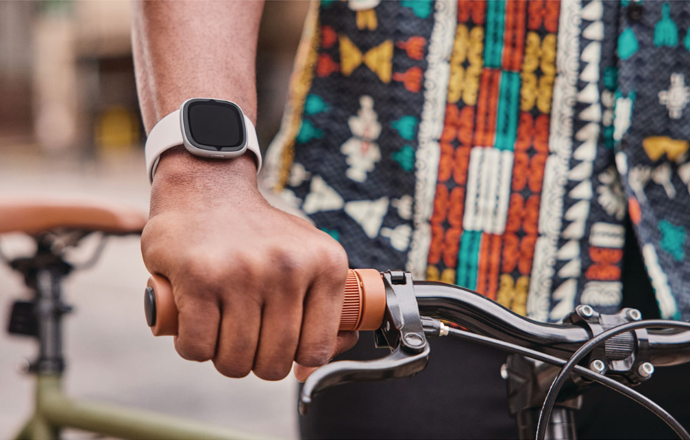 Homme qui fait du vélo et qui porte la montre intelligente Sense 2 de Fitbit.