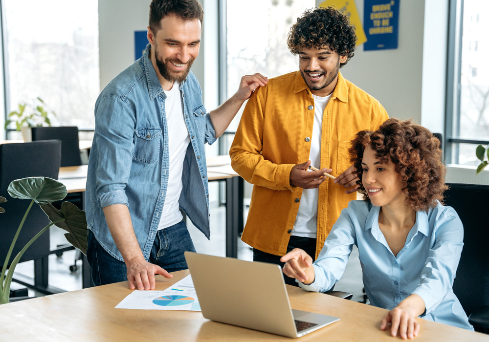 Un groupe de personnes dans un bureau se réunit autour d'un portable.