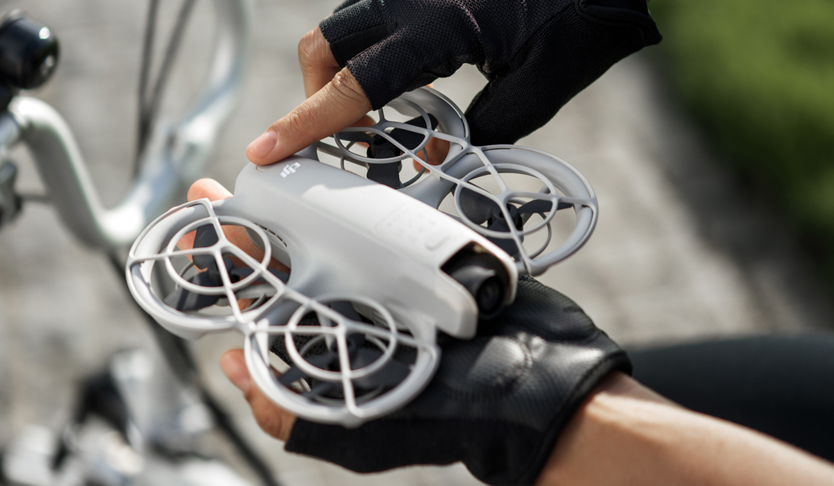 Man holding DJI Neo in palm of left hand.