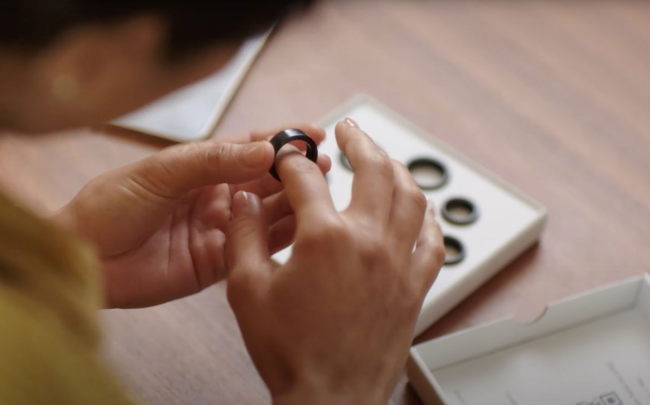 Woman trying ring sizes with the Oura sizing kit. 