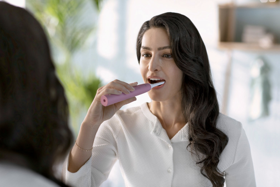 Woman brushing her teeth with the Philip Sonicare 4100 electric toothbrush