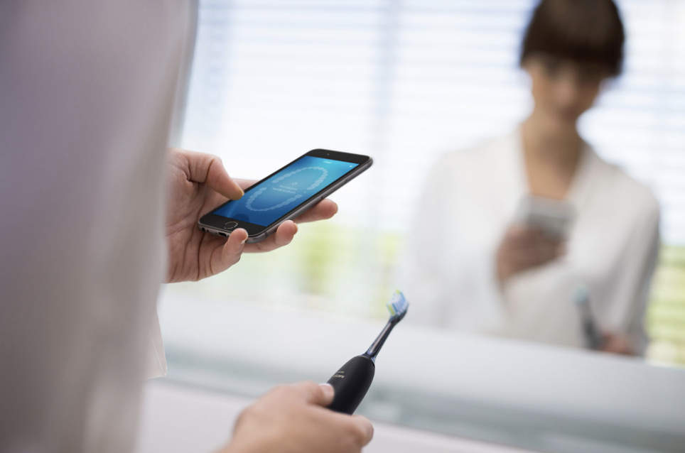 Woman using the app with Philips Sonicare DiamondClean electric toothbrush