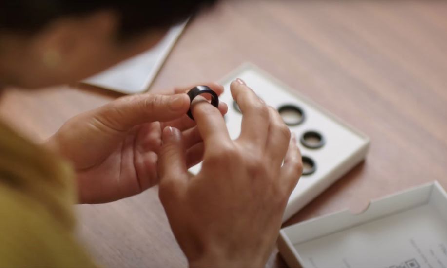 Woman trying ring sizes with the Oura sizing kit. 