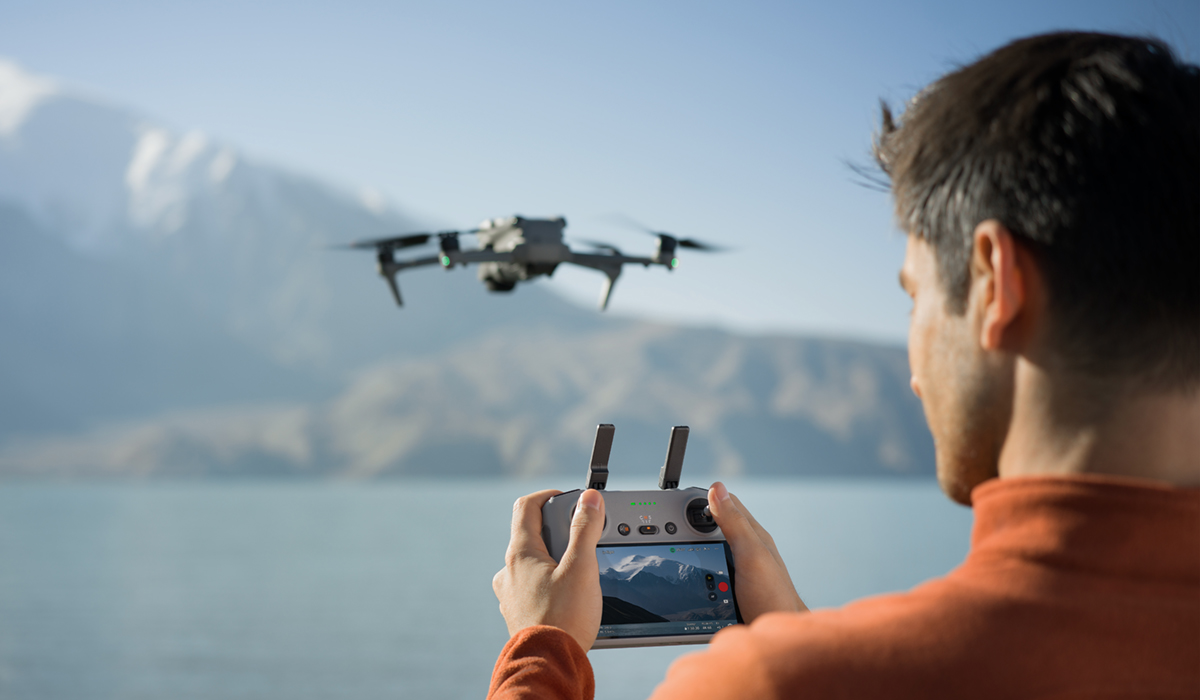 Man piloting DJI Ar 3S drone over a lake.