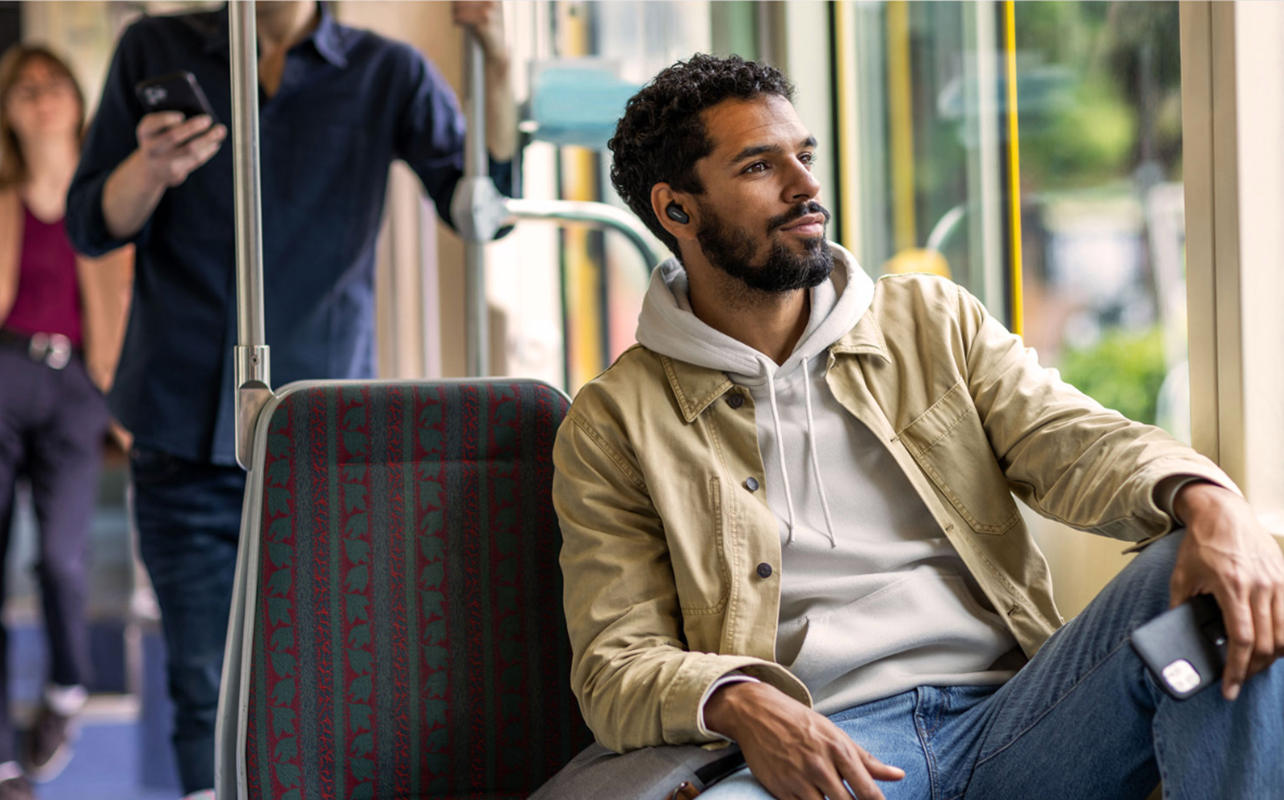 Man wearing noise cancelling earbuds in bus.