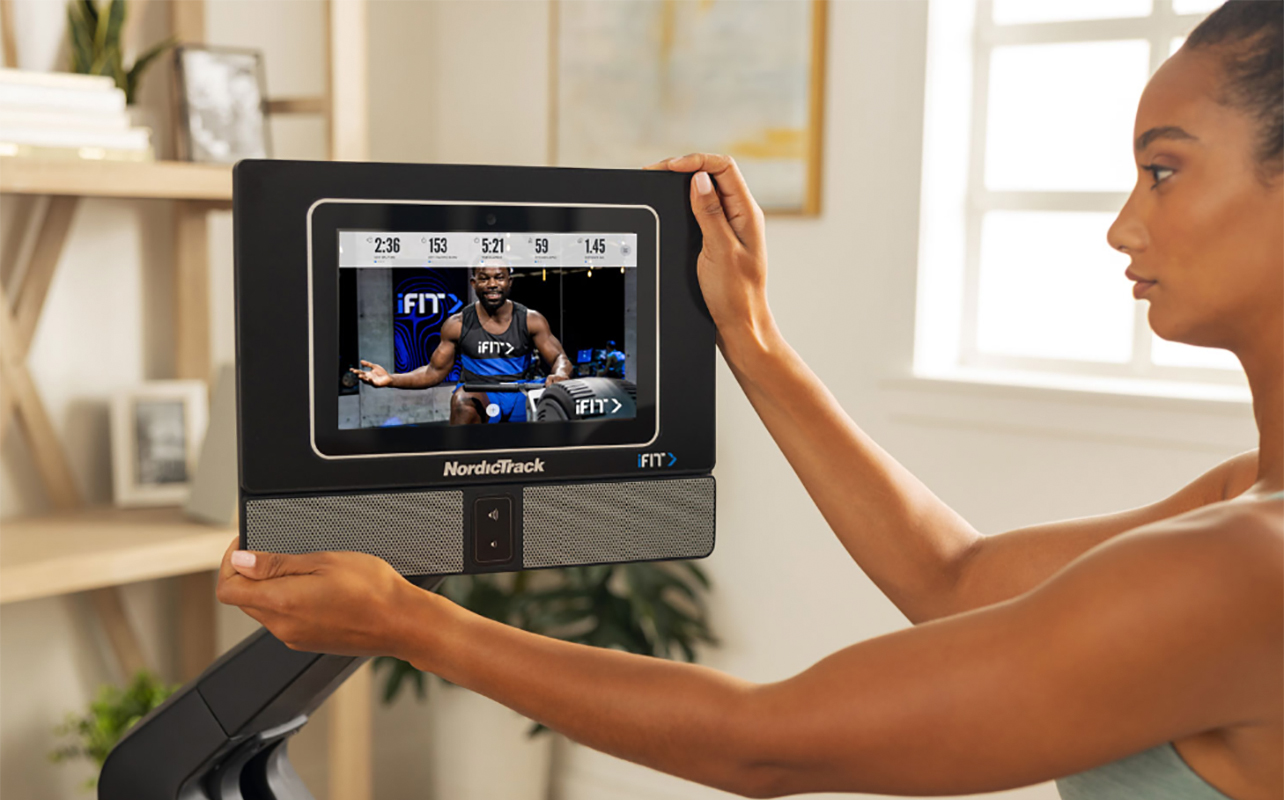 A woman adjusting the screen on a NordicTrack RW700 rowing machine