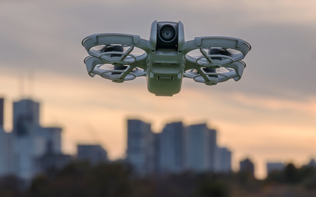 DJI Neo drone in flight with skyline behind.