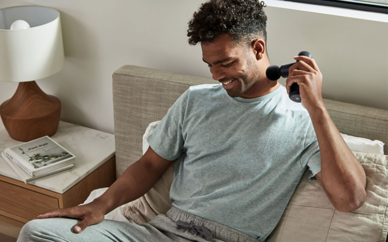 A man with a percussion massage device