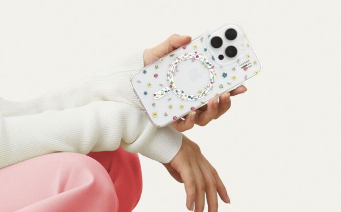 A hand holding an iPhone 16 with the Petite Floral clear Ideal of Sweden phone case against a white background. This person has pink pants and white sleeves but we cannot see their face.