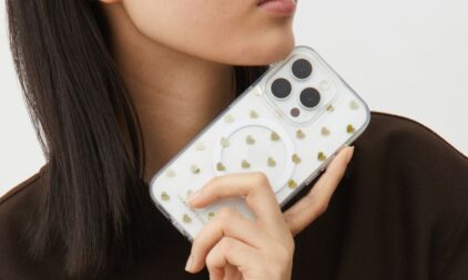 Someone holding an iPhone 16 with a clear Ideal of Sweden phone case with gold hearts on it. 