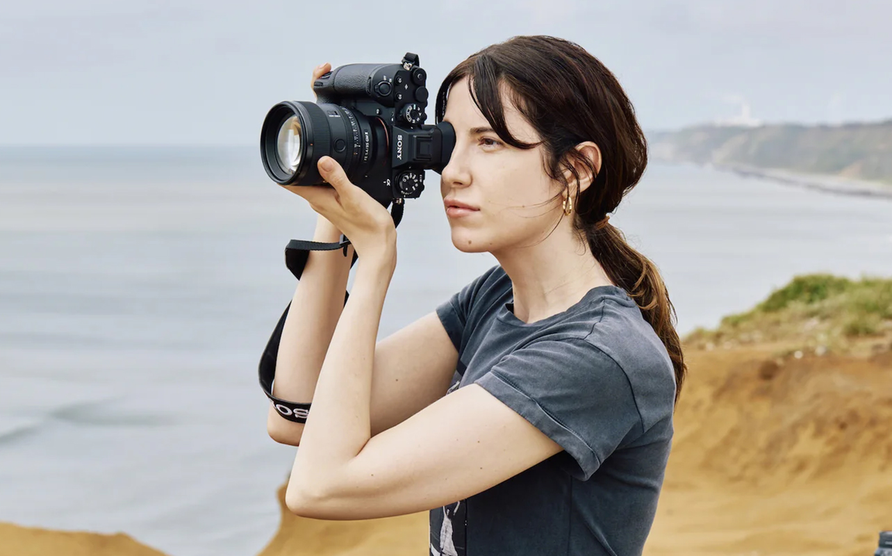 Woman taking photos with Sony Alpha 1 II outdoors.