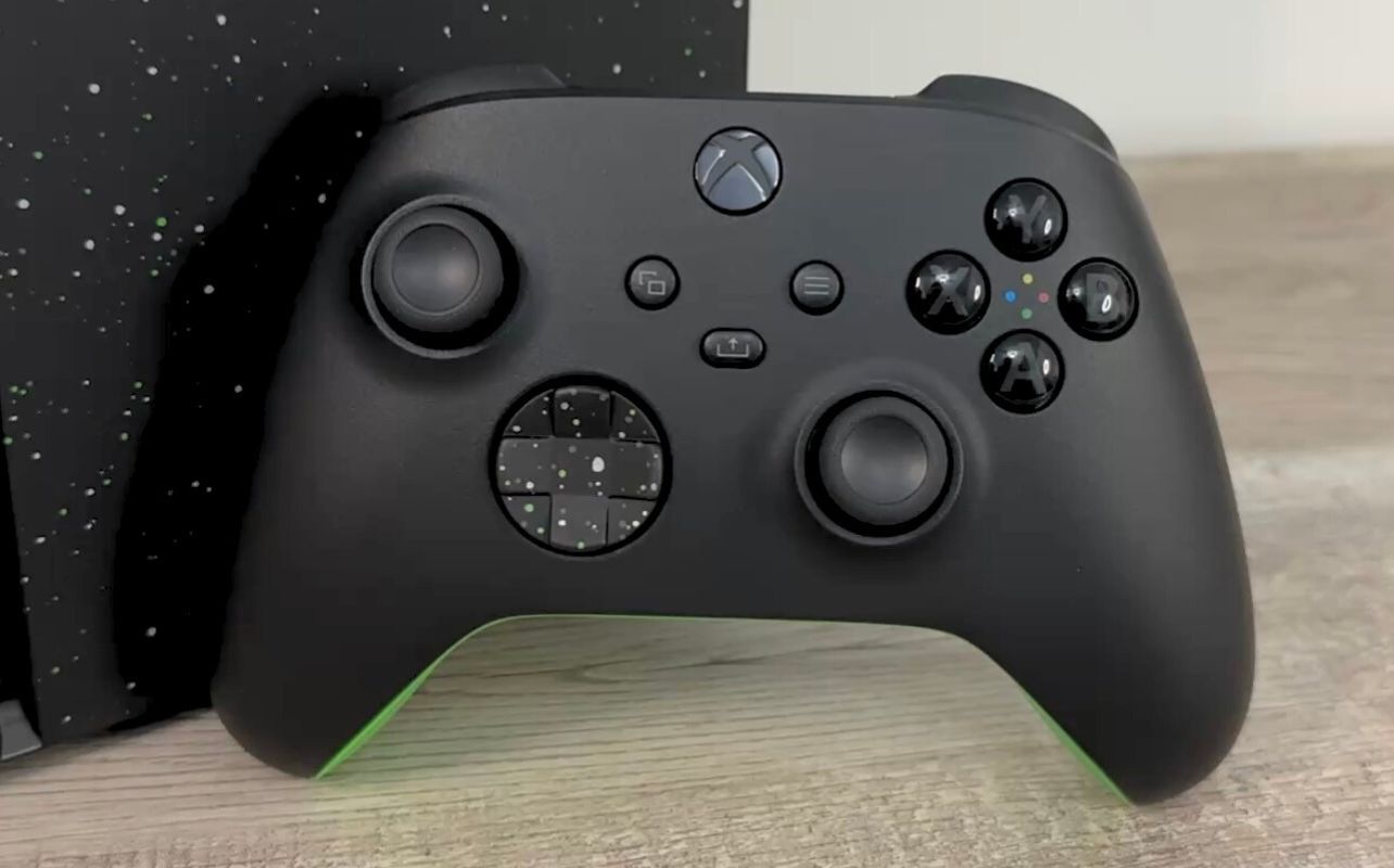 A close up look at the Xbox Series X Galaxy Black controller sitting on a desk leaning against the console.