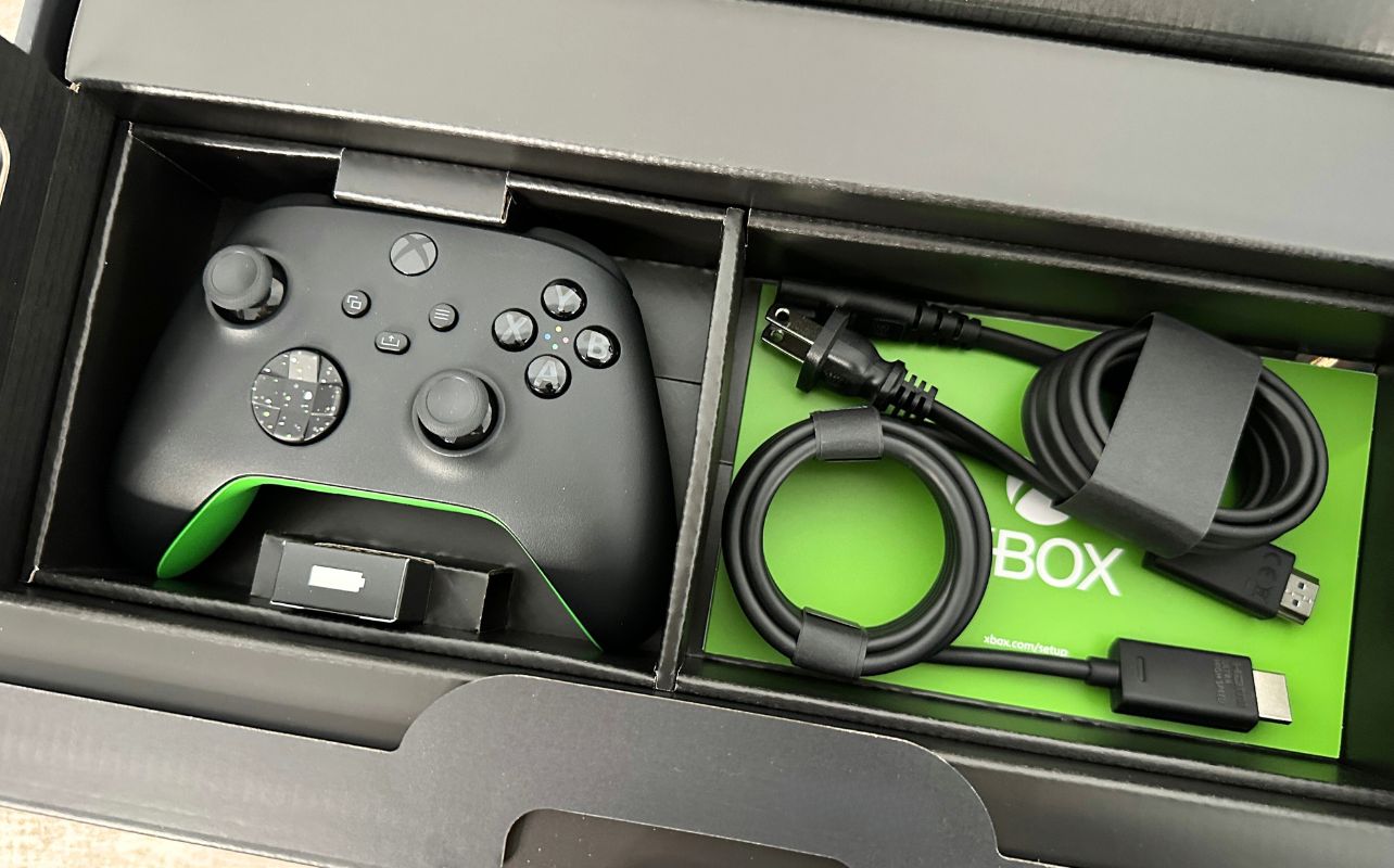 Xbox Series X Galaxy Black Special Edition top of box open revealing a controller, batteries, power and HDMI cable sitting on a desk.