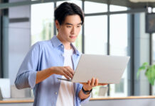 Man holding laptop in hand while using trackpad.