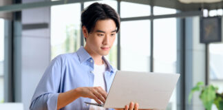 Man holding laptop in hand while using trackpad.