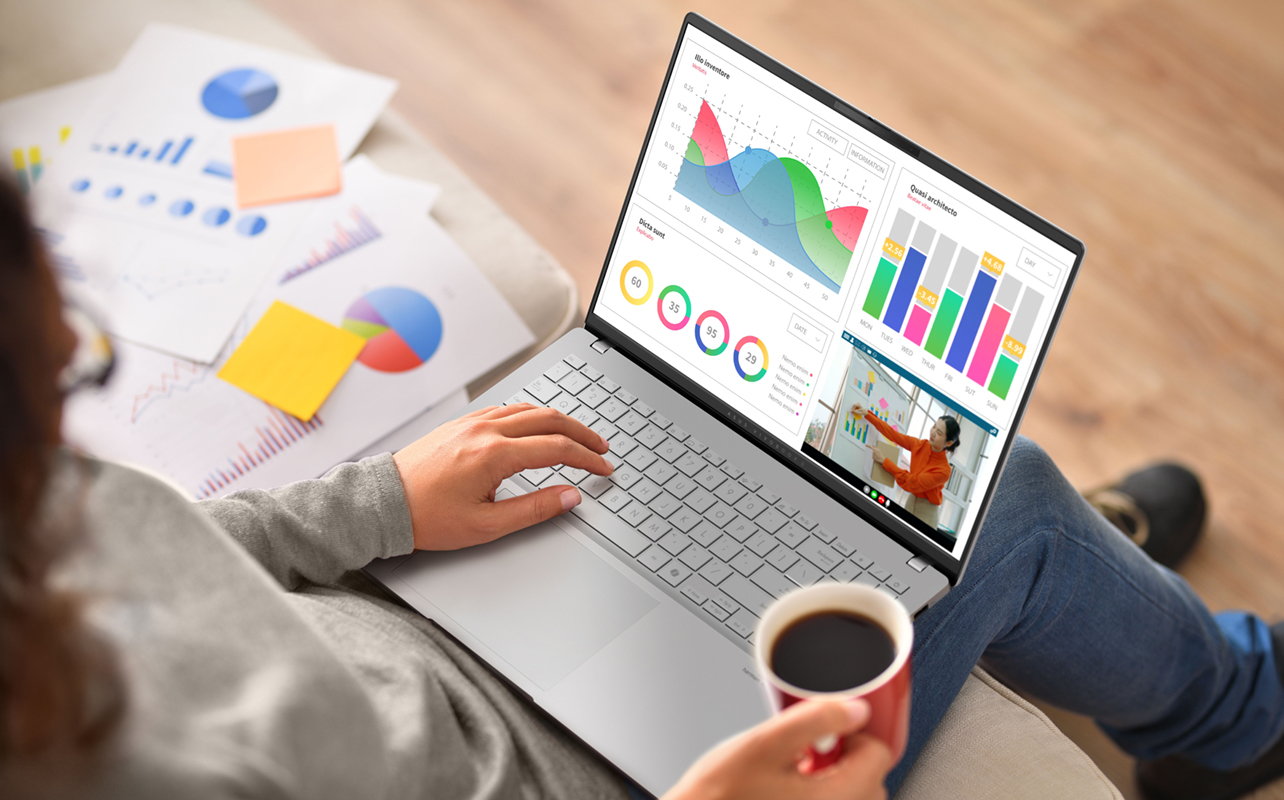 Woman working on charts with a laptop resting on lap.