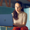 Woman sitting in chair working on HP Elitebook laptop.