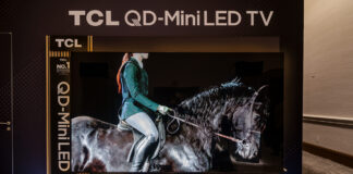 TCL 115QM7K TV on a stand at a CES 2025 showcase.